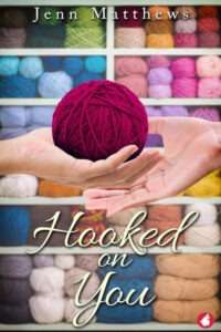 A book cover for "Hooked on You" by Jenn Matthews. The image features a pair of hands holding a ball of fuchsia yarn. In the blurred background, shelves are filled with numerous colorful skeins of yarn, suggesting a craft store or yarn shop. The title "Hooked on You" is in a flowing cream script in the bottom half of the cover. The author's name, Jenn Matthews, is in white text at the top.