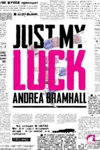 A contemporary book cover for "Just My Luck" by Andrea Bramhall. The cover has a distressed newspaper-like background with blurred text and dotted lines. The title "JUST MY LUCK" is prominently featured in bold, contrasting fonts: "JUST MY" in black and "LUCK" in bright pink. A blurry image of what appears to be a person or a scene with some blue elements is subtly visible through the text. The author's name, Andrea Bramhall, is in black text below the title, with a black line below it.